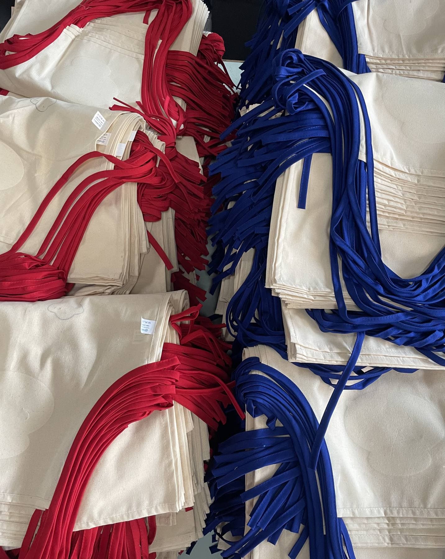 Grembiuli in cotone naturale con lacci rossi e blu, pronti per la consegna